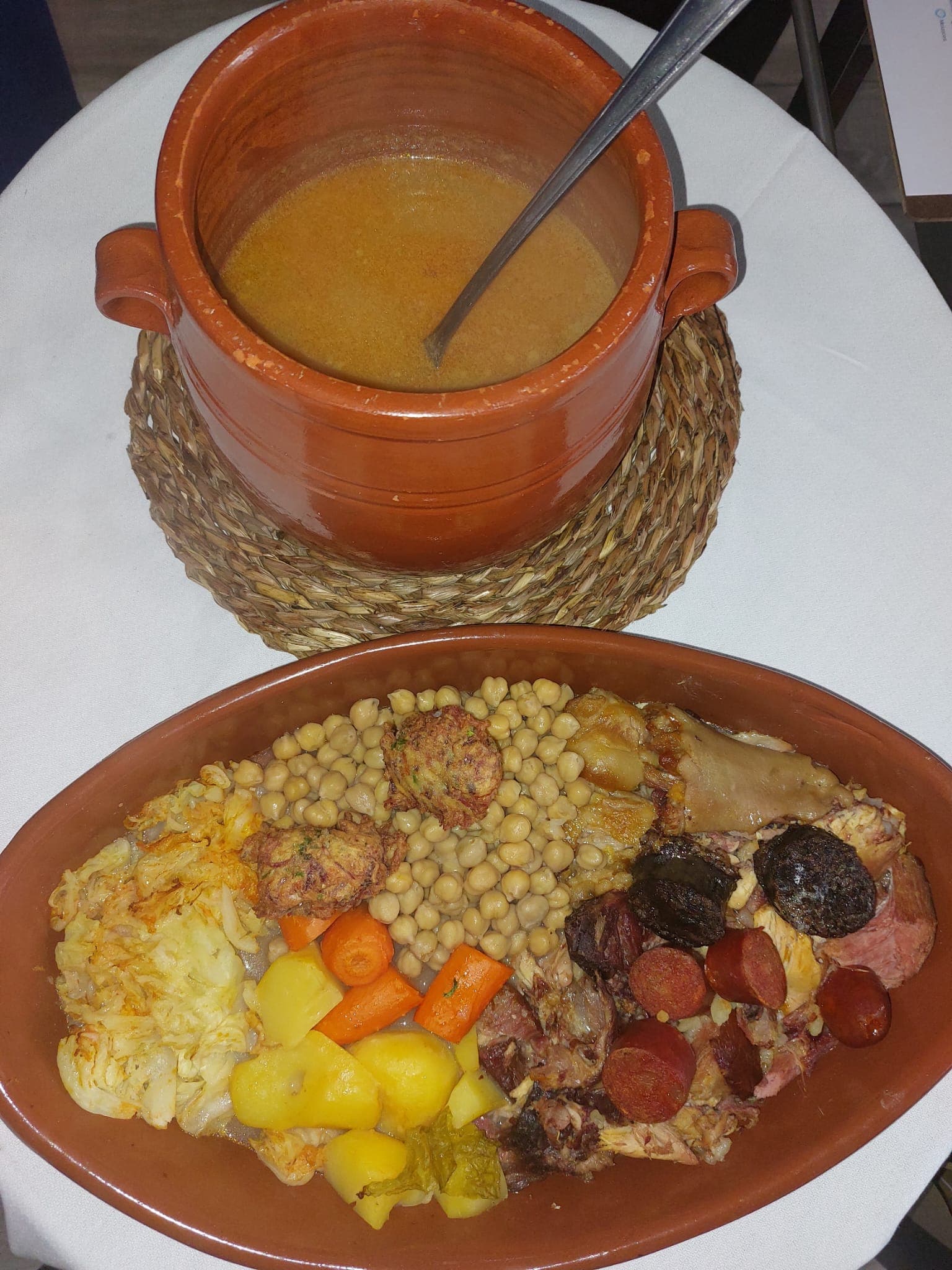 Cazuela de barro con el cocido madrileño montado: garbanzos, carnes y verdura