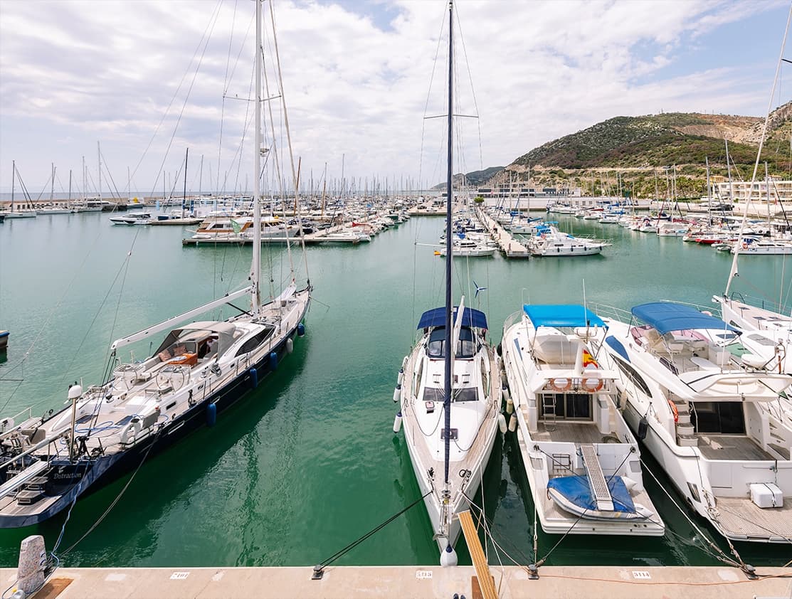 Veleros amarrados en Port Ginesta con el macizo del Garraf al fondo